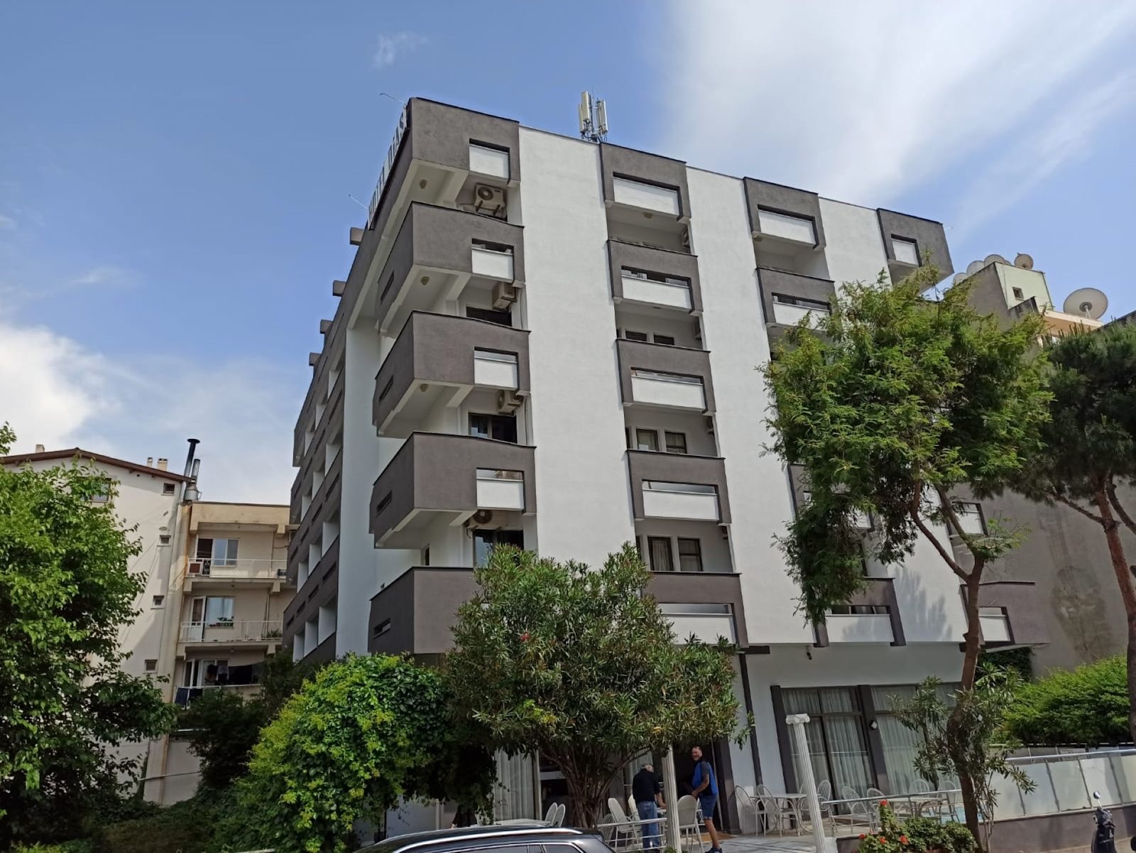 Ağaçlarla çevrili otel cephesi ve giriş katındaki teras